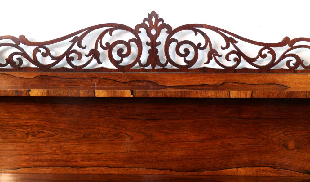An antique Regency open rosewood bookcase featuring an inverted breakfront profile, multi-tier shelving, and an intricately carved fretwork gallery. View XX
