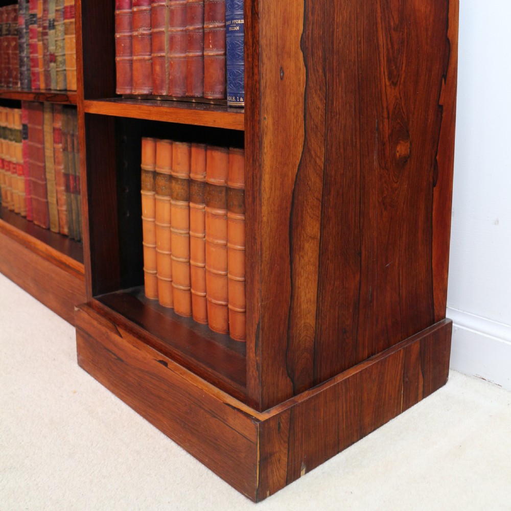 An antique Regency open rosewood bookcase featuring an inverted breakfront profile, multi-tier shelving, and an intricately carved fretwork gallery. View XXI