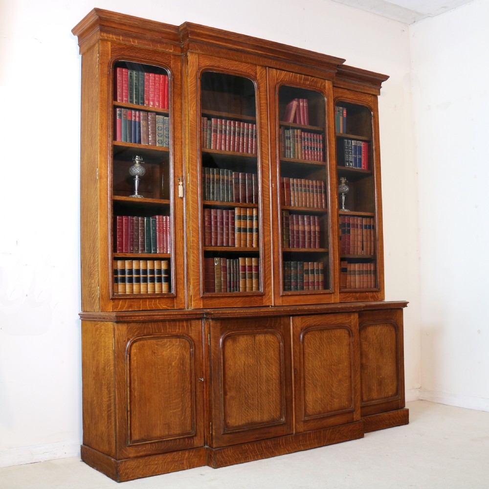 A large William IV golden oak breakfront bookcase featuring glazed upper doors above panelled wooden cupboard doors. View II