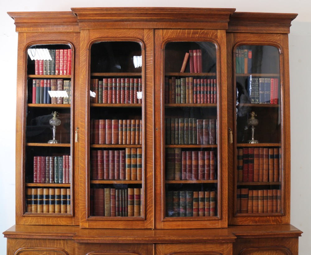 A large William IV golden oak breakfront bookcase featuring glazed upper doors above panelled wooden cupboard doors. View V