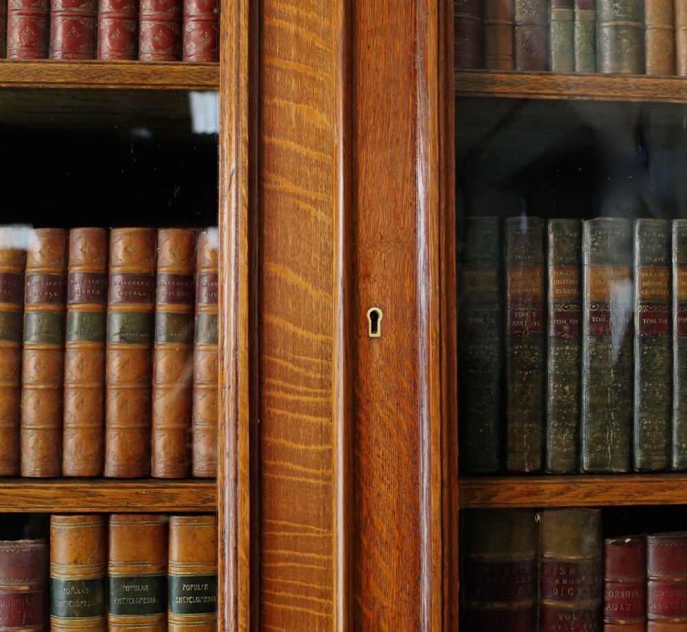 A large William IV golden oak breakfront bookcase featuring glazed upper doors above panelled wooden cupboard doors. View XIII