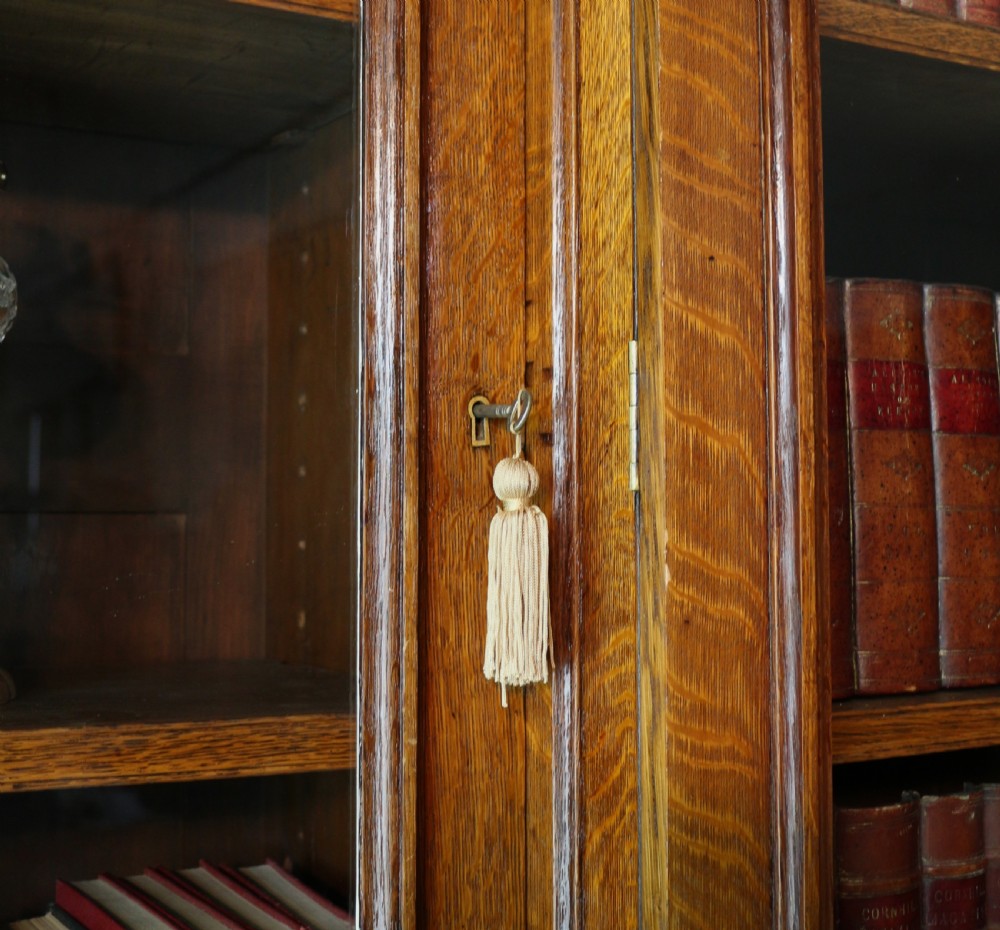 A large William IV golden oak breakfront bookcase featuring glazed upper doors above panelled wooden cupboard doors. View XIV