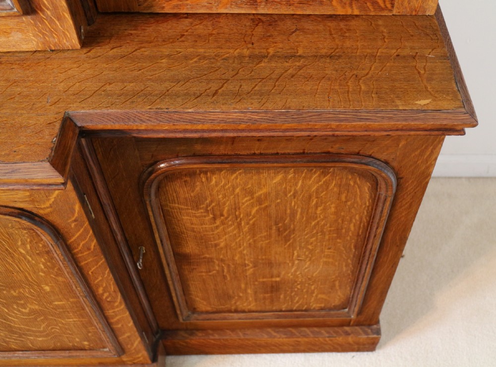 A large William IV golden oak breakfront bookcase featuring glazed upper doors above panelled wooden cupboard doors. View XIX