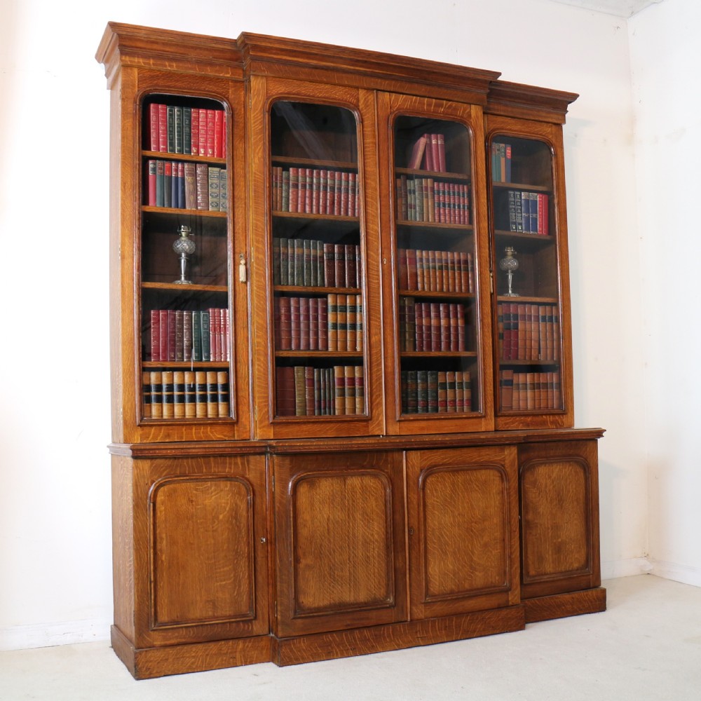 A large William IV golden oak breakfront bookcase featuring glazed upper doors above panelled wooden cupboard doors. View XXI