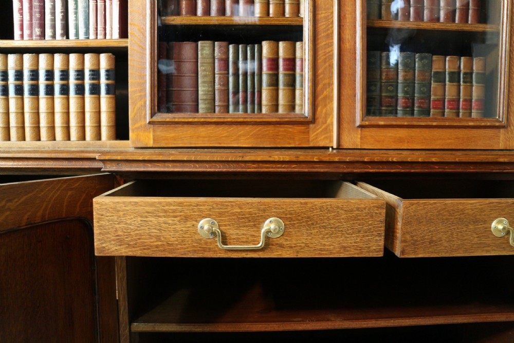 A large William IV golden oak breakfront bookcase featuring glazed upper doors above panelled wooden cupboard doors. View XXII