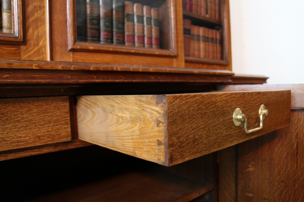 A large William IV golden oak breakfront bookcase featuring glazed upper doors above panelled wooden cupboard doors. View XXIII