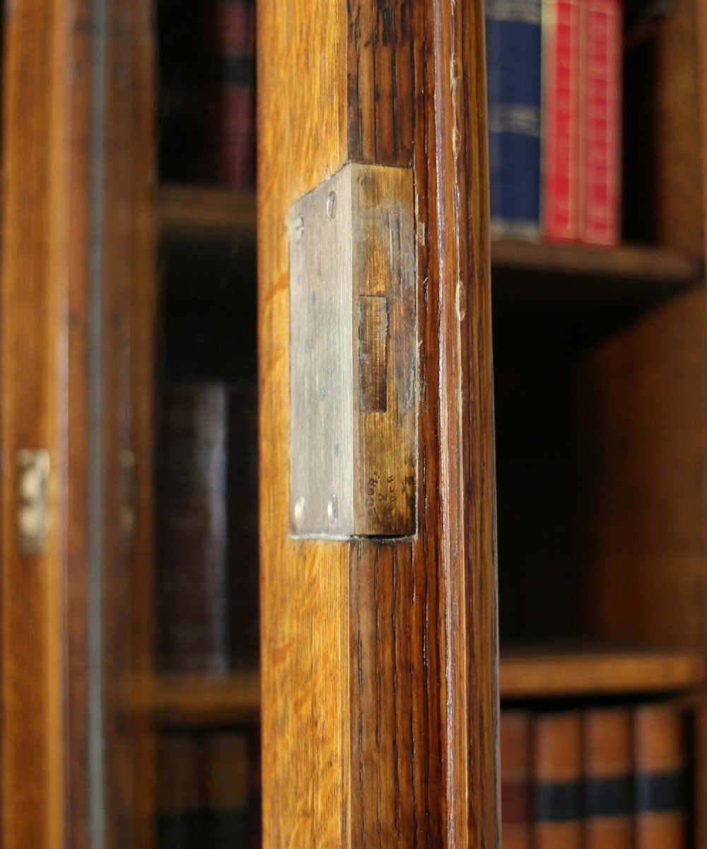 A large William IV golden oak breakfront bookcase featuring glazed upper doors above panelled wooden cupboard doors. View XXIV