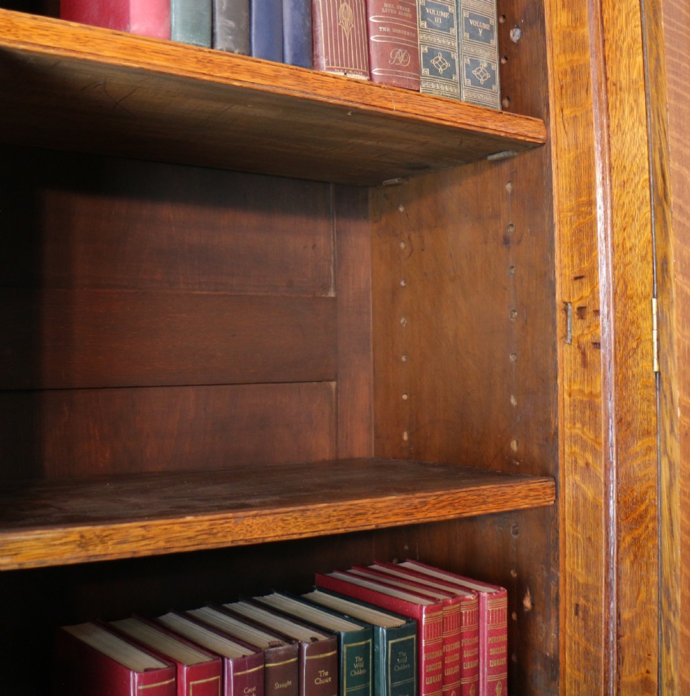 A large William IV golden oak breakfront bookcase featuring glazed upper doors above panelled wooden cupboard doors. View XXV