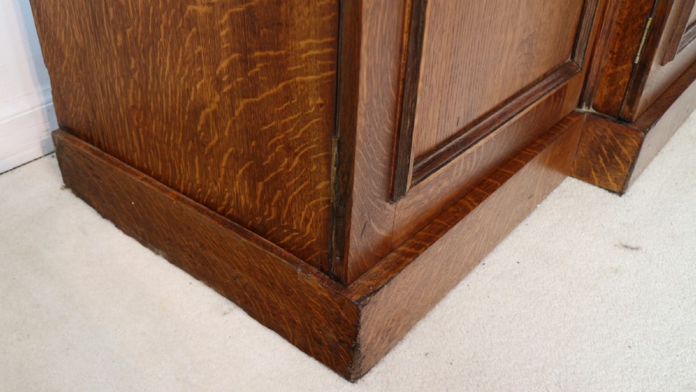 A large William IV golden oak breakfront bookcase featuring glazed upper doors above panelled wooden cupboard doors. View XXIX