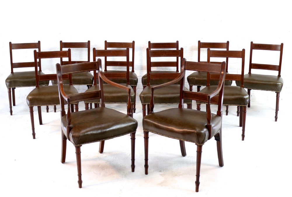 A set of twelve George III mahogany dining chairs featuring rectangular bar-back cresting rails with string inlay, green leather upholstered seats with stud detailing, and turned front legs. View III