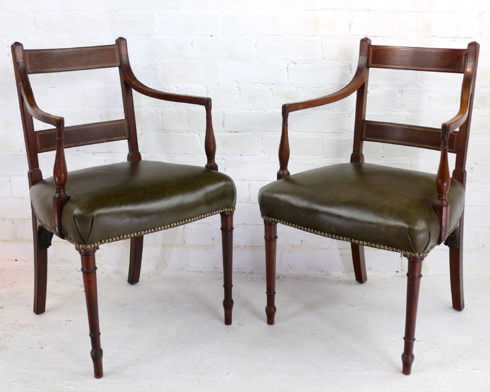 A set of twelve George III mahogany dining chairs featuring rectangular bar-back cresting rails with string inlay, green leather upholstered seats with stud detailing, and turned front legs. View IX
