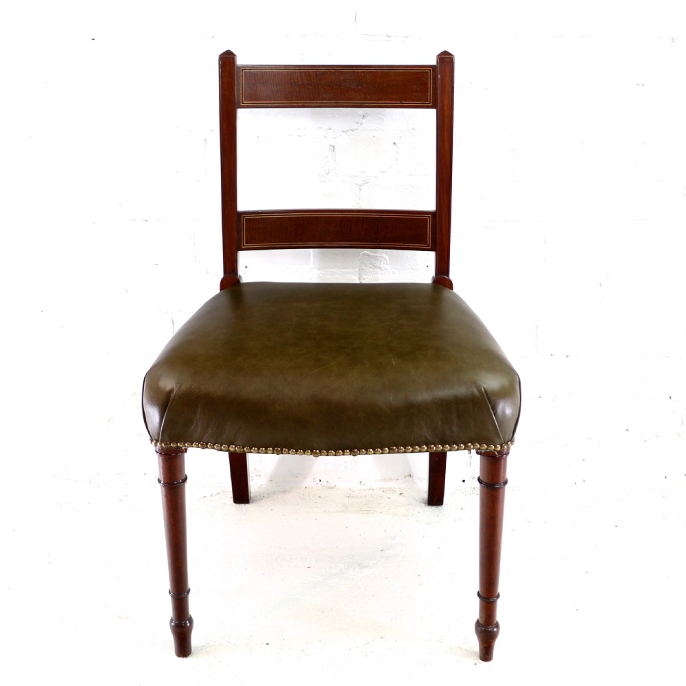 A set of twelve George III mahogany dining chairs featuring rectangular bar-back cresting rails with string inlay, green leather upholstered seats with stud detailing, and turned front legs. View XIII