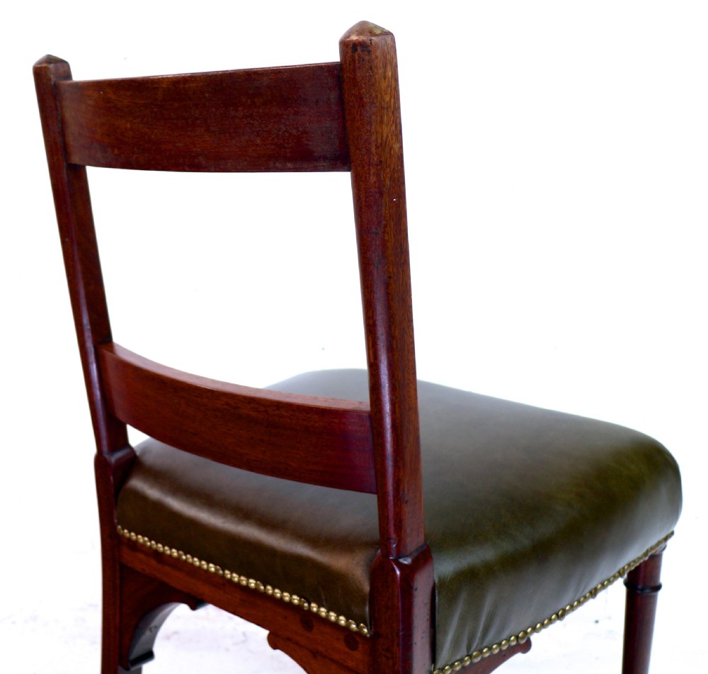 A set of twelve George III mahogany dining chairs featuring rectangular bar-back cresting rails with string inlay, green leather upholstered seats with stud detailing, and turned front legs. View XX
