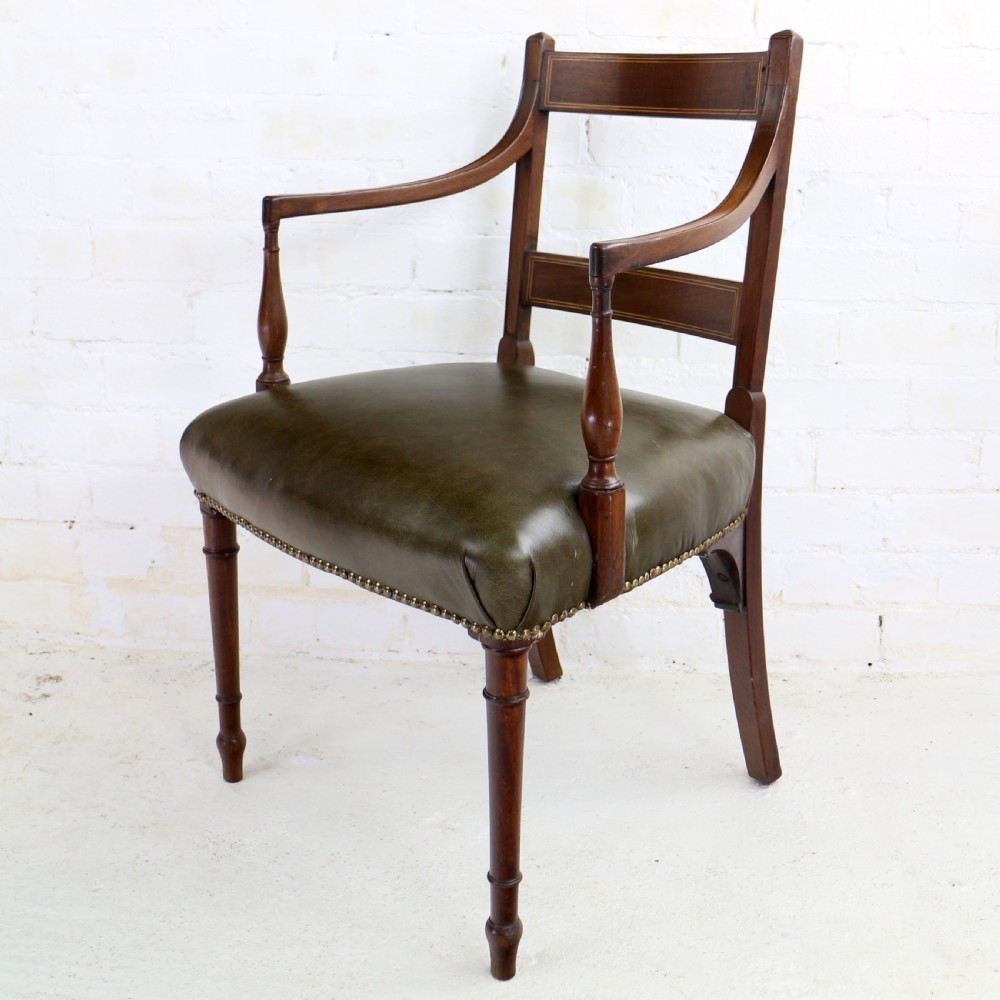 A set of twelve George III mahogany dining chairs featuring rectangular bar-back cresting rails with string inlay, green leather upholstered seats with stud detailing, and turned front legs. View XXII