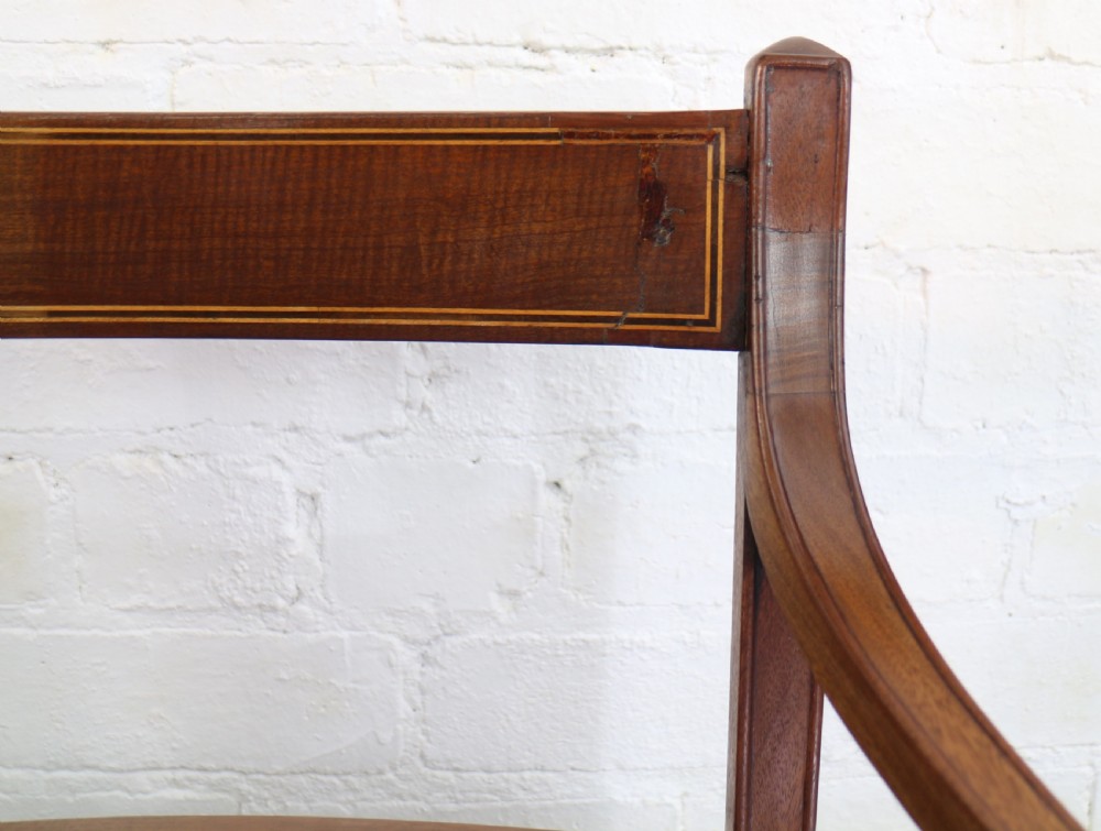 A set of twelve George III mahogany dining chairs featuring rectangular bar-back cresting rails with string inlay, green leather upholstered seats with stud detailing, and turned front legs. View XXV