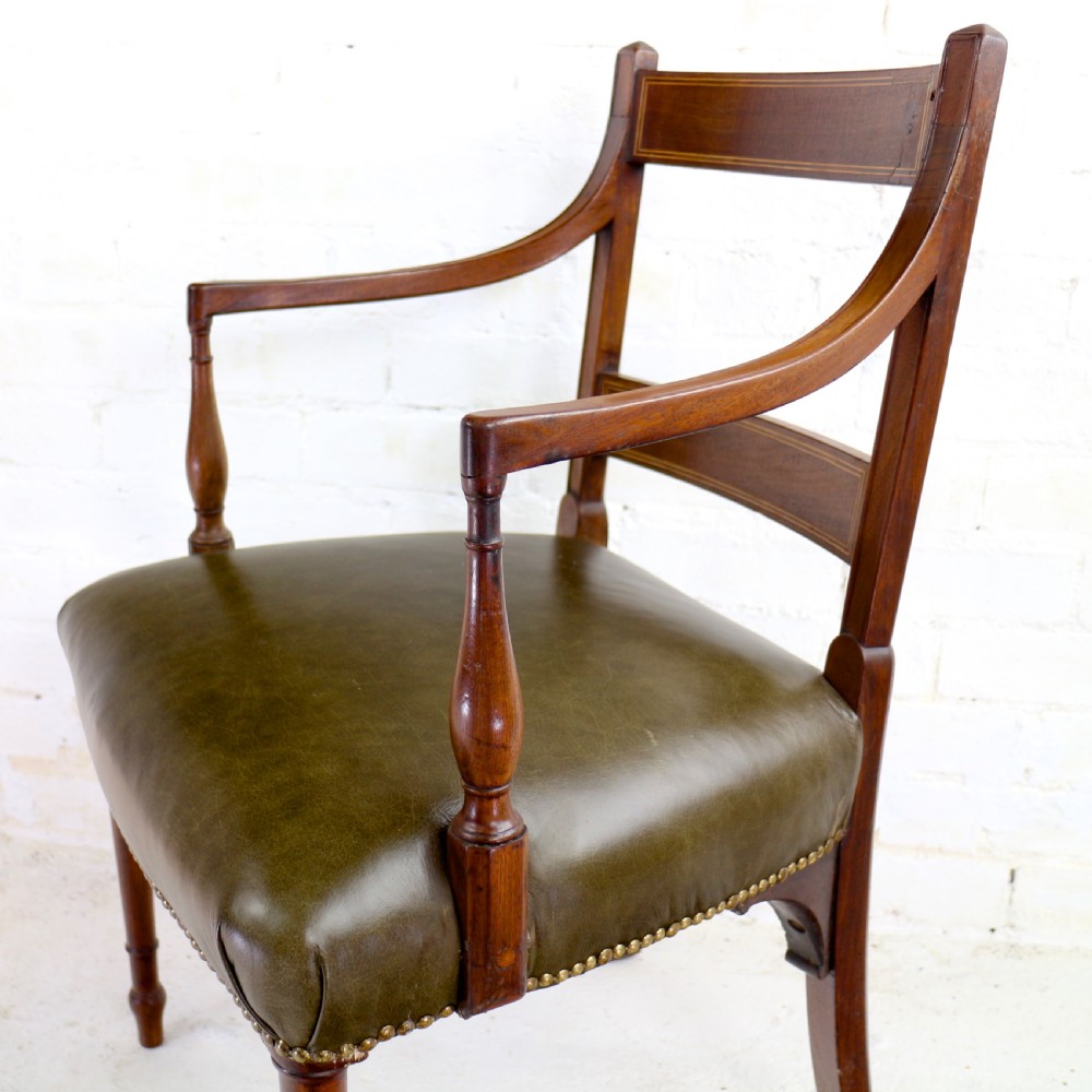 A set of twelve George III mahogany dining chairs featuring rectangular bar-back cresting rails with string inlay, green leather upholstered seats with stud detailing, and turned front legs. View XXVII