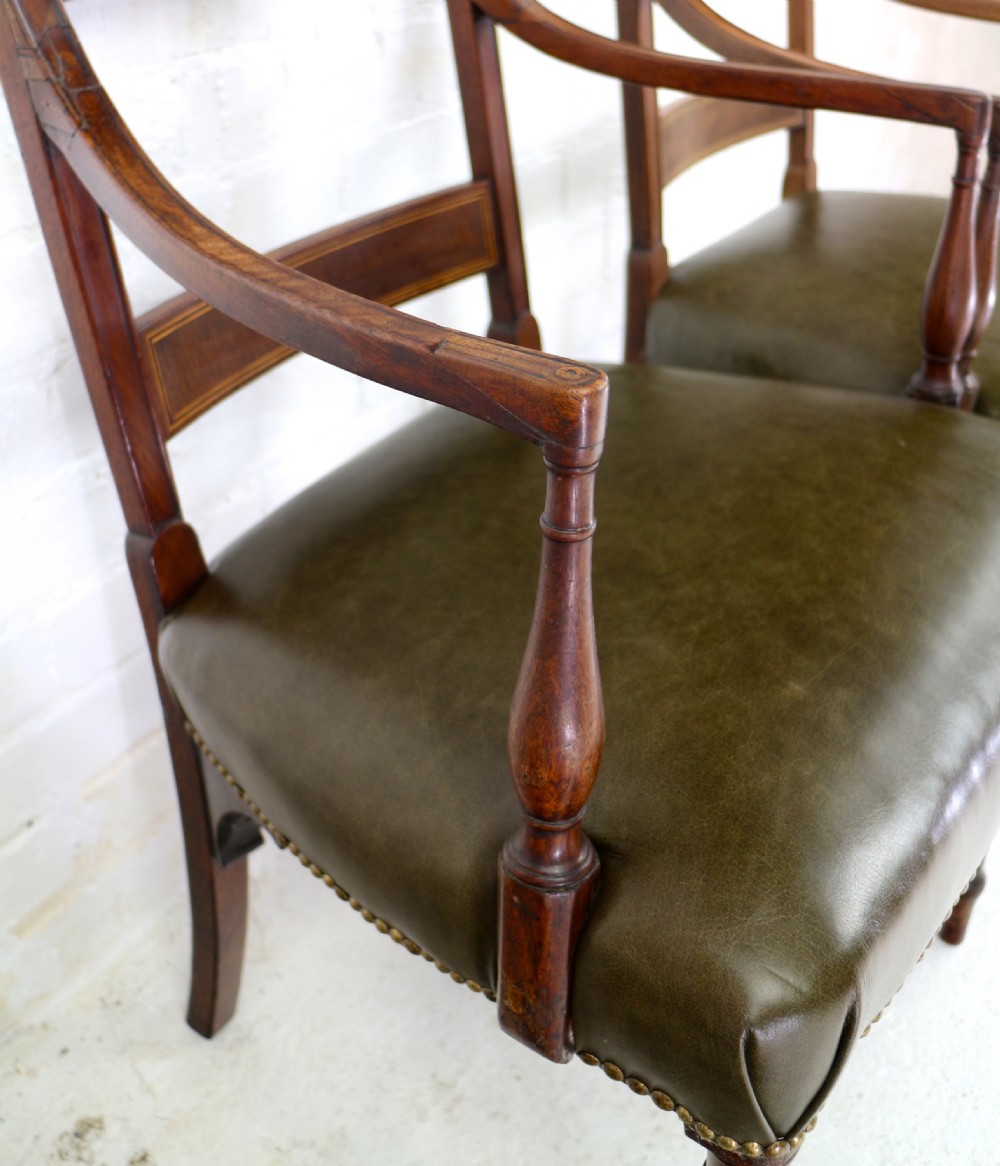 A set of twelve George III mahogany dining chairs featuring rectangular bar-back cresting rails with string inlay, green leather upholstered seats with stud detailing, and turned front legs. View XXVIII