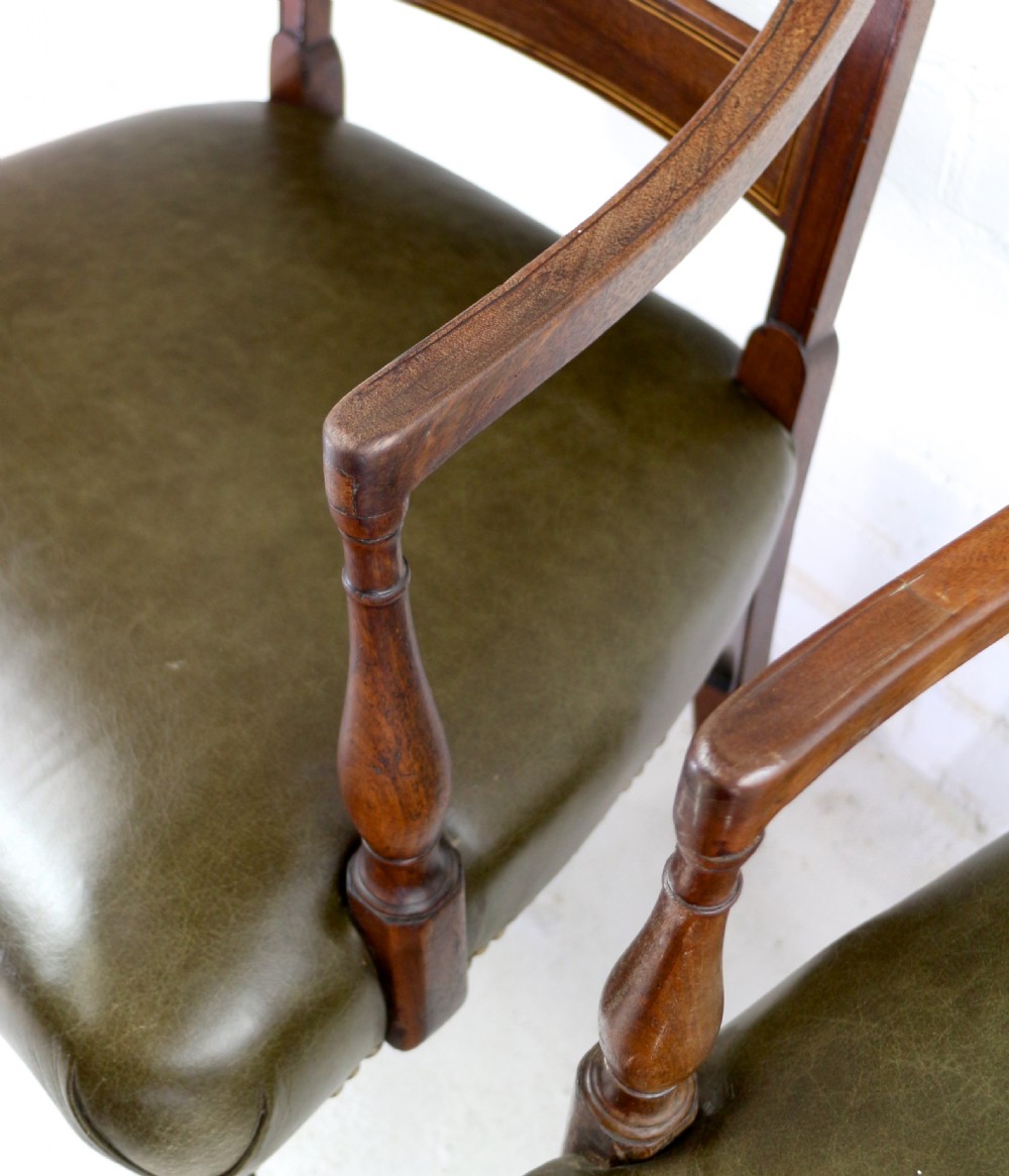 A set of twelve George III mahogany dining chairs featuring rectangular bar-back cresting rails with string inlay, green leather upholstered seats with stud detailing, and turned front legs. View XXIX