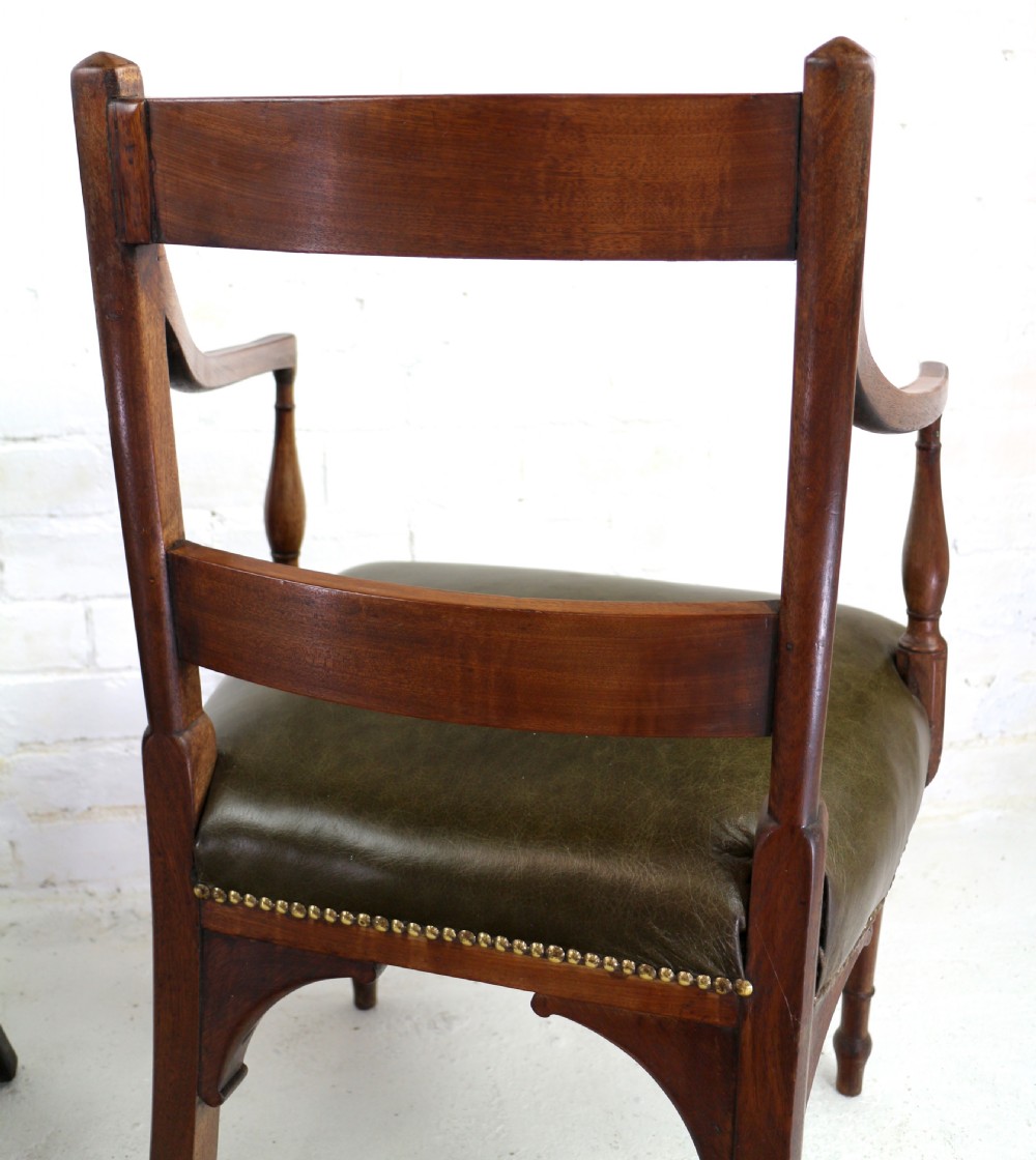 A set of twelve George III mahogany dining chairs featuring rectangular bar-back cresting rails with string inlay, green leather upholstered seats with stud detailing, and turned front legs. View XXX