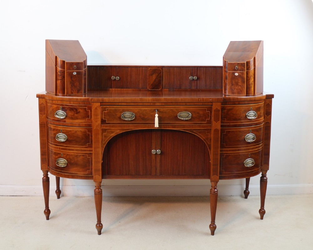 A George III Scottish flame mahogany stage-back sideboard featuring curved side drawers, inlay details, central tambour cupboards, and slender turned legs. View III