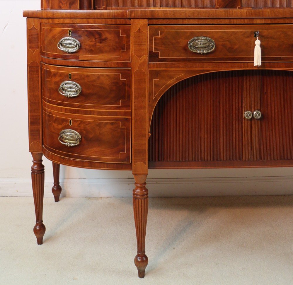 A George III Scottish flame mahogany stage-back sideboard featuring curved side drawers, inlay details, central tambour cupboards, and slender turned legs. View IX