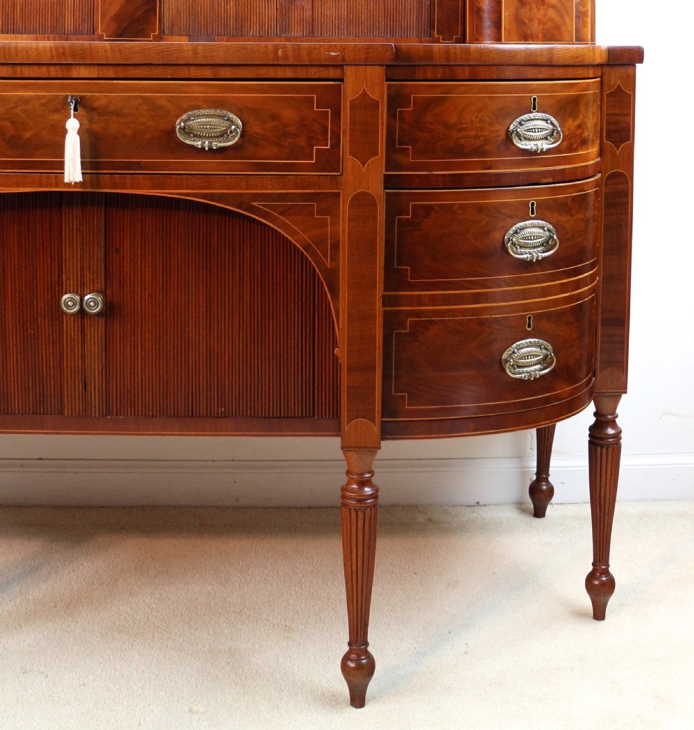 A George III Scottish flame mahogany stage-back sideboard featuring curved side drawers, inlay details, central tambour cupboards, and slender turned legs. View X