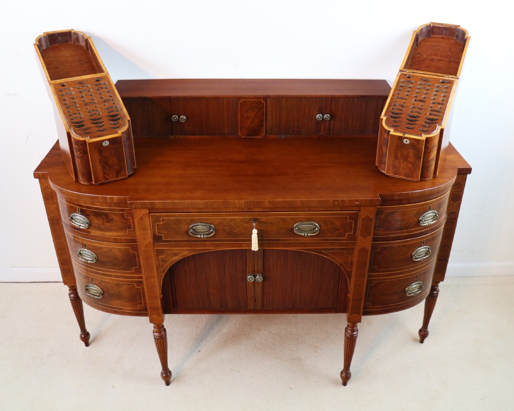 A George III Scottish flame mahogany stage-back sideboard featuring curved side drawers, inlay details, central tambour cupboards, and slender turned legs. View XVI