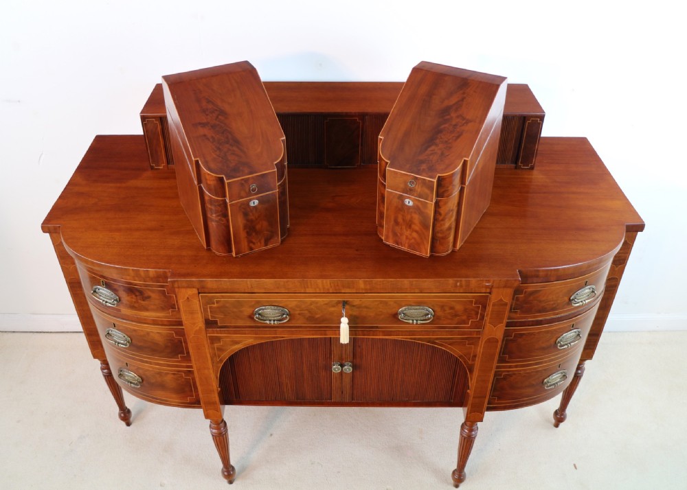 A George III Scottish flame mahogany stage-back sideboard featuring curved side drawers, inlay details, central tambour cupboards, and slender turned legs. View XVII