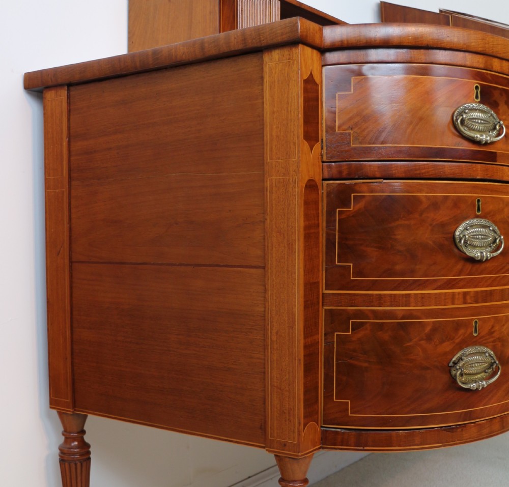 A George III Scottish flame mahogany stage-back sideboard featuring curved side drawers, inlay details, central tambour cupboards, and slender turned legs. View XXIII