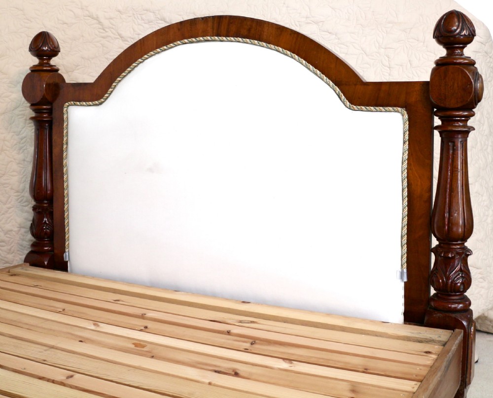 A Victorian mahogany double bed featuring a high arched upholstered headboard, a flame mahogany footboard with carved posts, and brass castors. View XIV