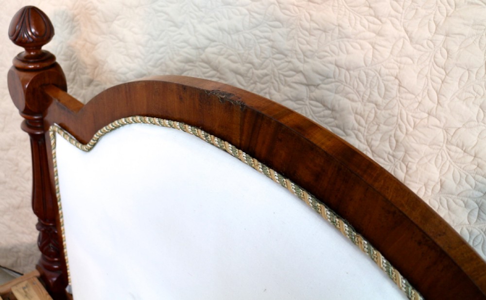 A Victorian mahogany double bed featuring a high arched upholstered headboard, a flame mahogany footboard with carved posts, and brass castors. View XVII