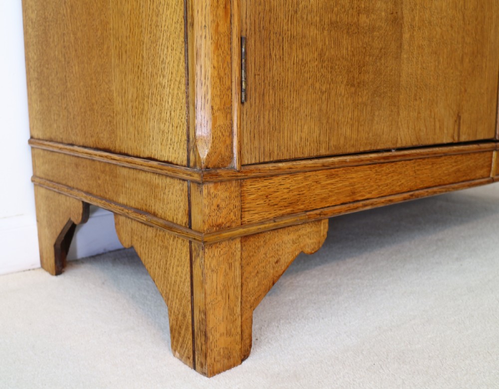 A three-piece golden oak Art Deco bedroom suite featuring a double wardrobe, dressing table with an arched mirror, and a small cupboard chest, all decorated with marquetry medallions. View XI