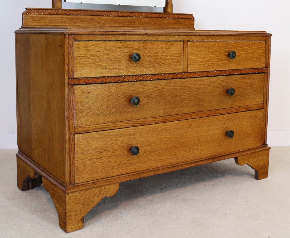 A three-piece golden oak Art Deco bedroom suite featuring a double wardrobe, dressing table with an arched mirror, and a small cupboard chest, all decorated with marquetry medallions. View XIV