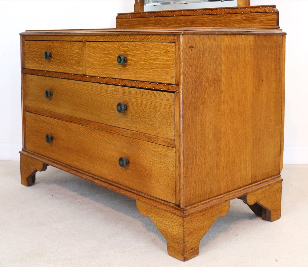 A three-piece golden oak Art Deco bedroom suite featuring a double wardrobe, dressing table with an arched mirror, and a small cupboard chest, all decorated with marquetry medallions. View XV