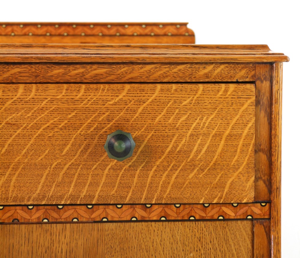 A three-piece golden oak Art Deco bedroom suite featuring a double wardrobe, dressing table with an arched mirror, and a small cupboard chest, all decorated with marquetry medallions. View XXV