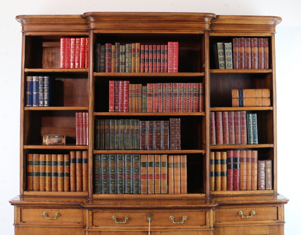 A large Victorian Gothic oak breakfront bookcase featuring open upper shelves filled with books and carved lower cupboard doors. View III