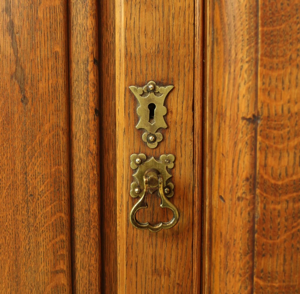 A large Victorian Gothic oak breakfront bookcase featuring open upper shelves filled with books and carved lower cupboard doors. View X