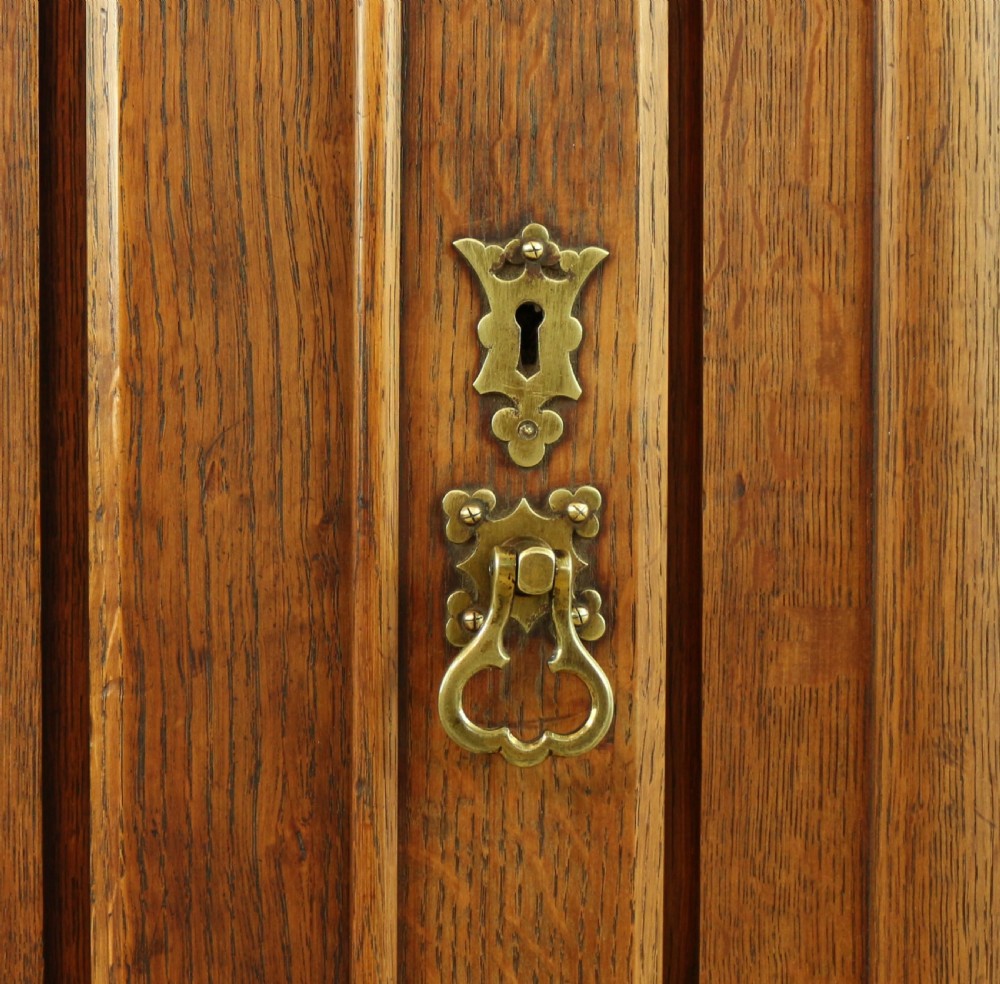 A large Victorian Gothic oak breakfront bookcase featuring open upper shelves filled with books and carved lower cupboard doors. View XI