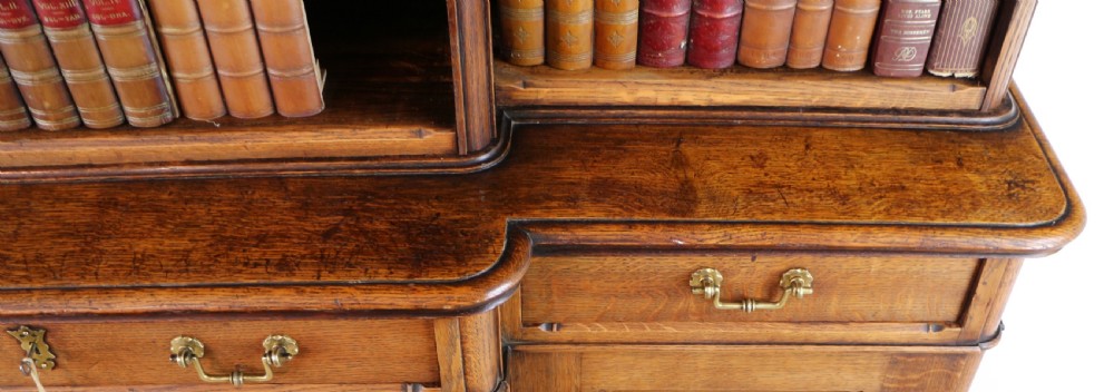 A large Victorian Gothic oak breakfront bookcase featuring open upper shelves filled with books and carved lower cupboard doors. View XIV
