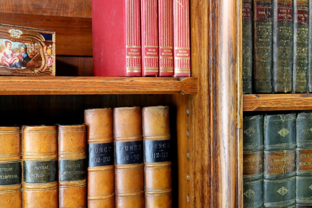 A large Victorian Gothic oak breakfront bookcase featuring open upper shelves filled with books and carved lower cupboard doors. View XVI