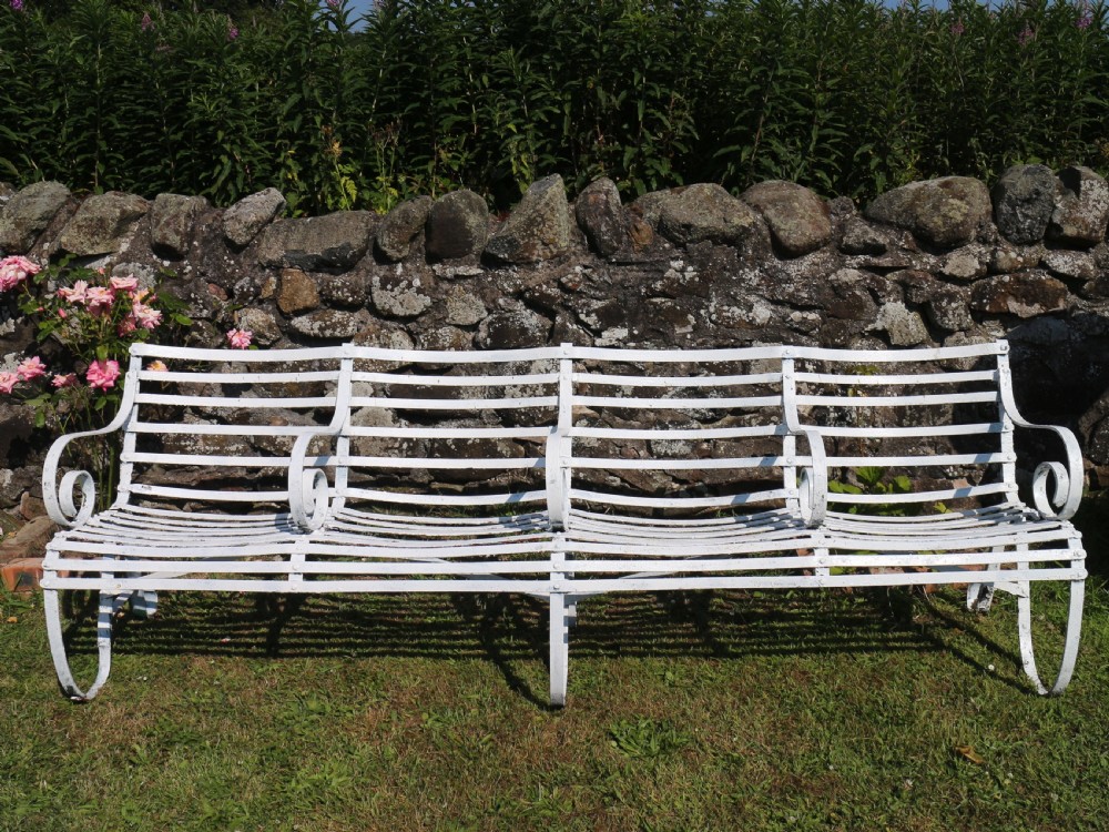 A pair of long white painted wrought iron Victorian garden benches with slatted backs and seats and scrolled armrests. View VII