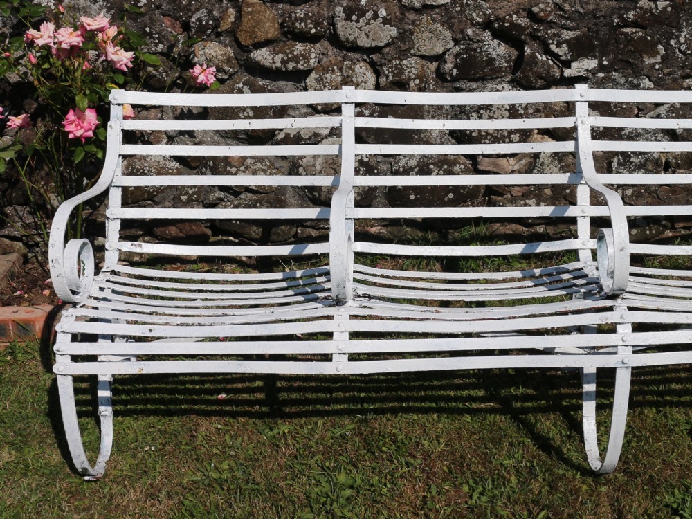 A pair of long white painted wrought iron Victorian garden benches with slatted backs and seats and scrolled armrests. View VIII