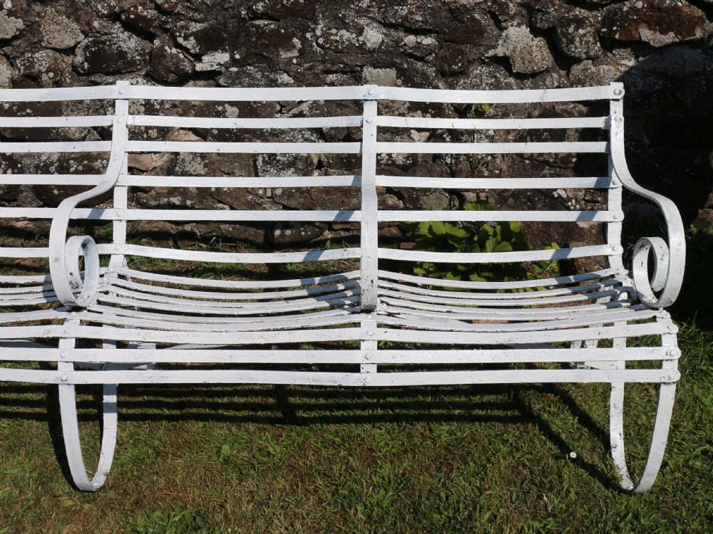 A pair of long white painted wrought iron Victorian garden benches with slatted backs and seats and scrolled armrests. View IX