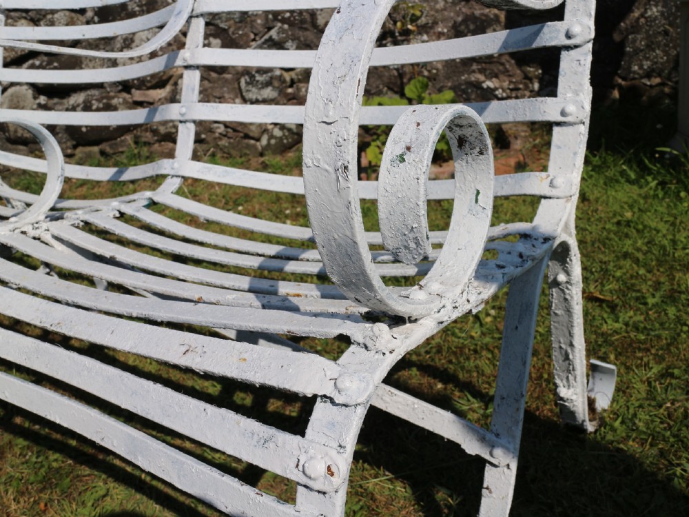 A pair of long white painted wrought iron Victorian garden benches with slatted backs and seats and scrolled armrests. View XIII