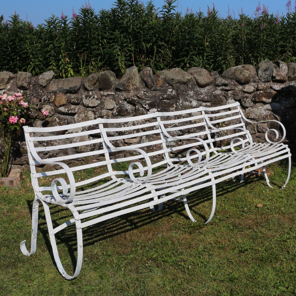 A pair of long white painted wrought iron Victorian garden benches with slatted backs and seats and scrolled armrests. View XVI