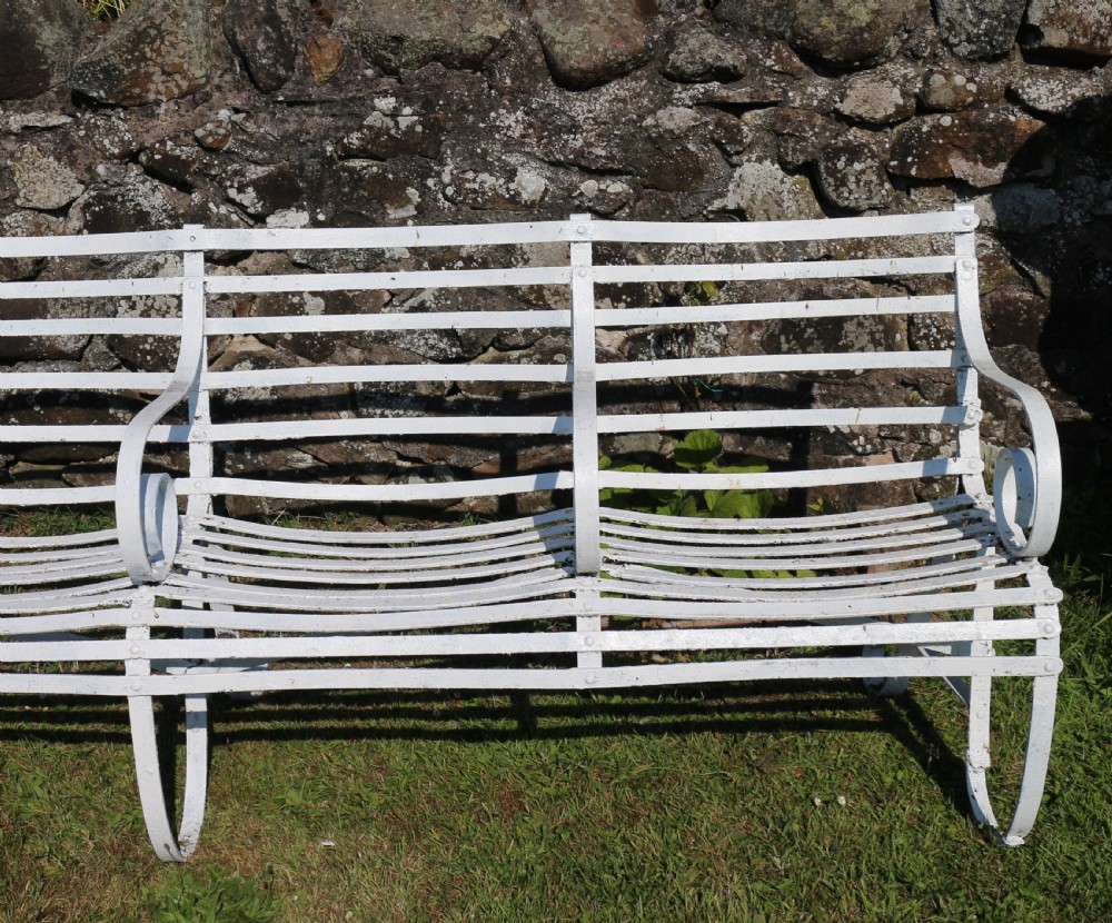 A pair of long white painted wrought iron Victorian garden benches with slatted backs and seats and scrolled armrests. View XX