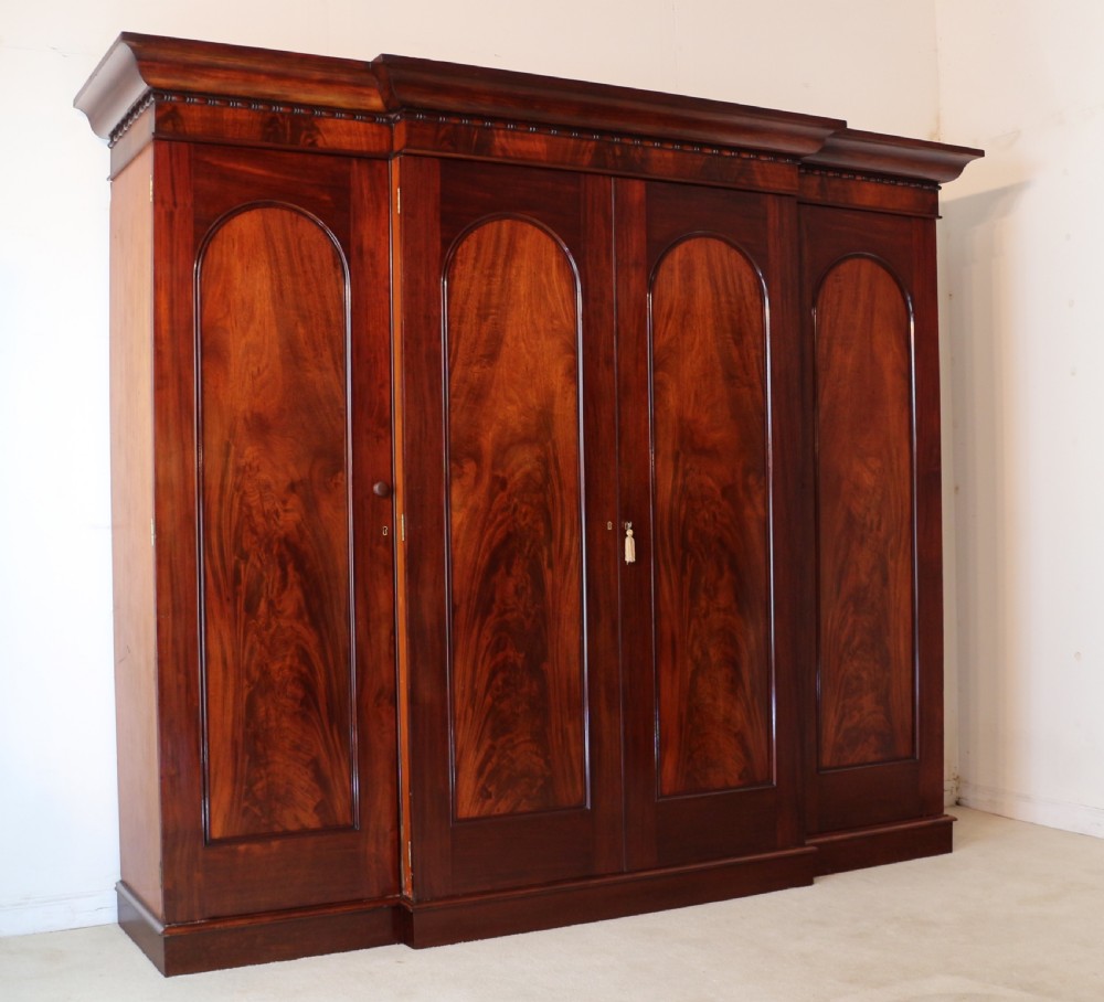 A nineteenth-century breakfront wardrobe featuring flame mahogany veneer, four arched panel doors, and a moulded projecting cornice. View II