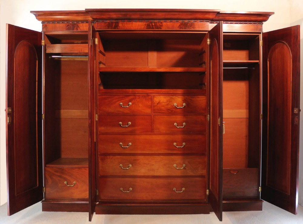A nineteenth-century breakfront wardrobe featuring flame mahogany veneer, four arched panel doors, and a moulded projecting cornice. View VII