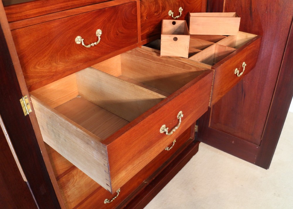 A nineteenth-century breakfront wardrobe featuring flame mahogany veneer, four arched panel doors, and a moulded projecting cornice. View XVII