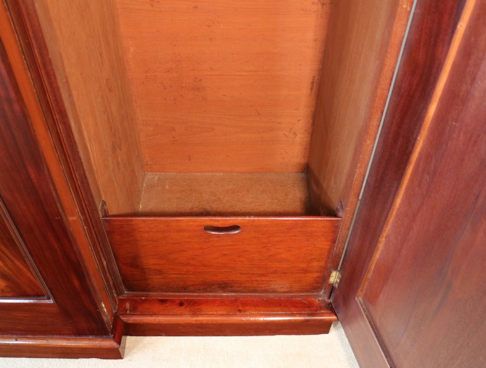 A nineteenth-century breakfront wardrobe featuring flame mahogany veneer, four arched panel doors, and a moulded projecting cornice. View XX